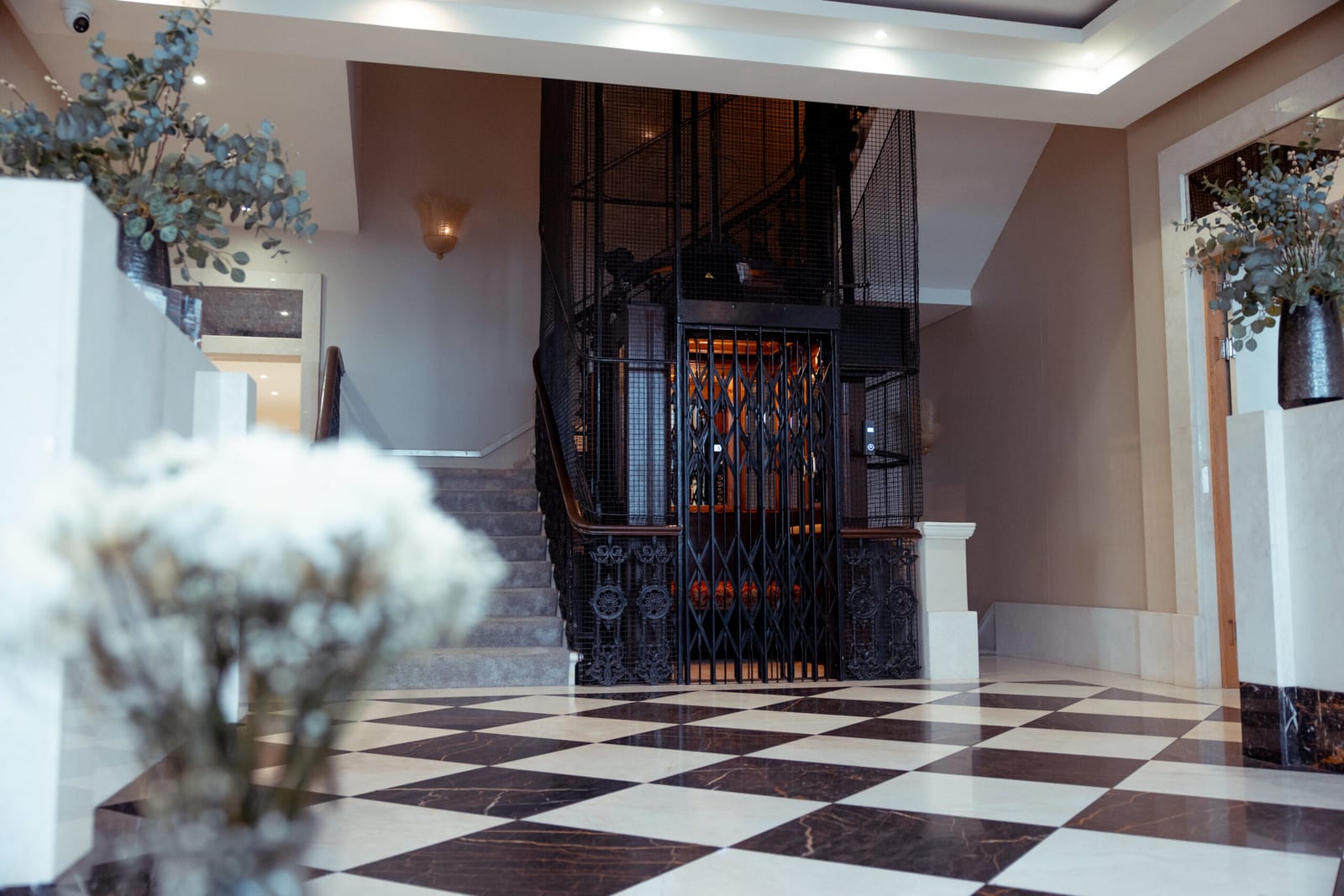 Hotel lobby with a chequerboard marble floor and period cage lift