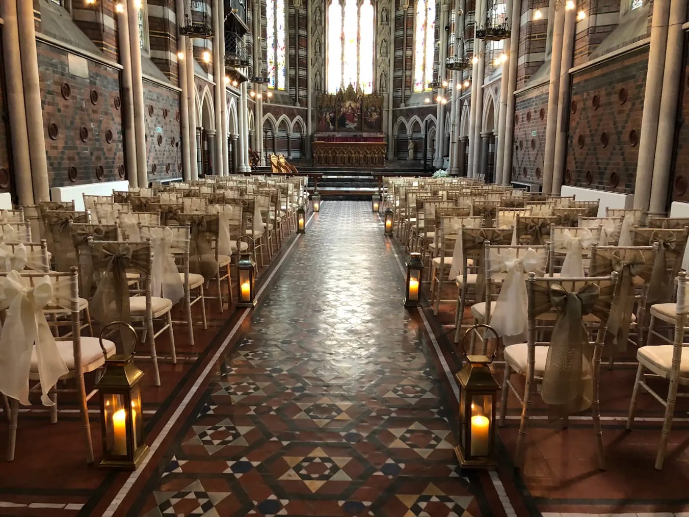 The nave of All Saints Chapel laid out for a wedding ceremony with lanterns along the aisle